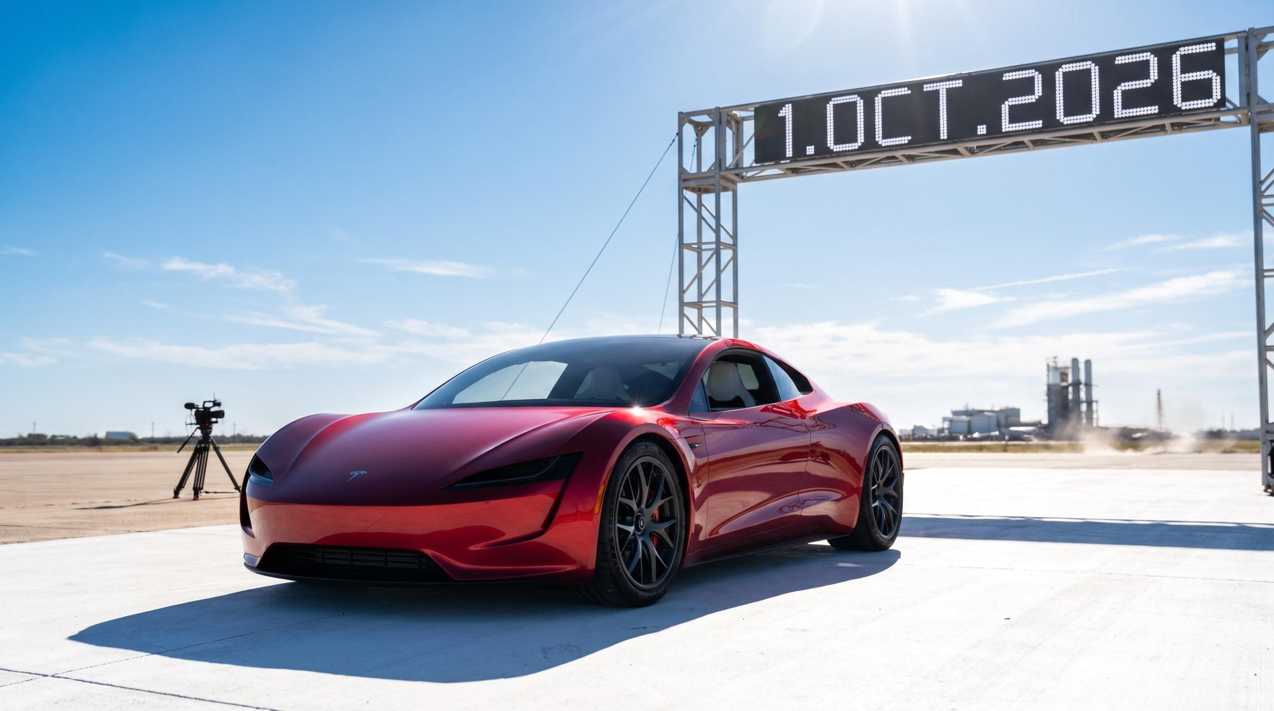 Tesla Roadster on Texas tarmac with 1.OCT.2026 reveal signage and SpaceX thruster nozzles visible