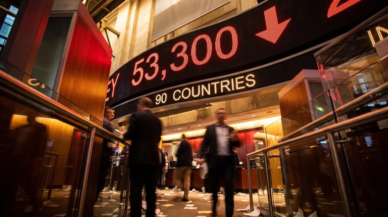 Dow Jones ticker board showing 53,300 drop on trading floor as Trump trade war tariff threat hits markets