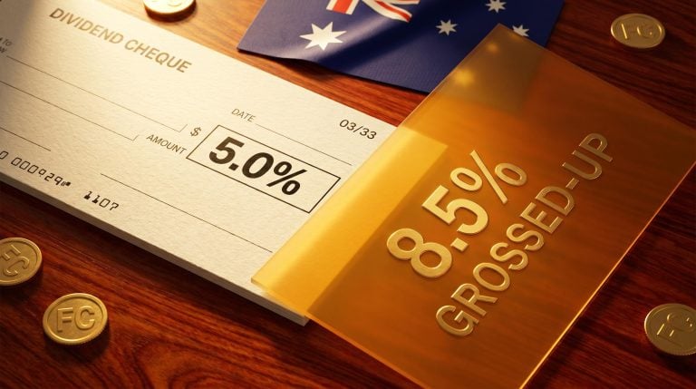 Physical dividend cheque showing 5.0% cash yield beneath a larger grossed-up 8.5% franking credit panel on jarrah wood